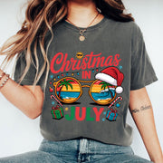 Festive Christmas in July Women's T-Shirt: Fun Holiday Graphic Tee Featuring Beach Scene, Sunglasses, and Santa Hat Design
 - 1